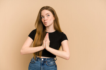 Wall Mural - Young redhead woman cut out isolated holding hands in pray near mouth, feels confident.