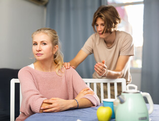 Wall Mural - Teenage boy asking for forgiveness from his upset mother sitting at home ..