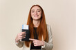 © Asier - Young red hair business woman holding a flight tickets isolated