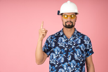 Worker with helmet and safety glasses pointing upward