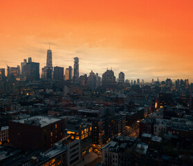 Wall Mural - Crowded buildings of the New York City skyline with warm yellow orange sky above the downtown skyscrapers of Manhattan