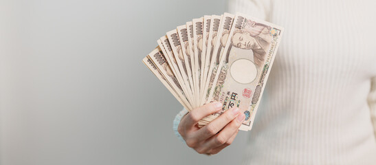 Woman hand holding Japanese Yen banknote stack. Thousand Yen money. Japan cash, Tax, Recession Economy, Inflation, Investment, finance and shopping payment concepts