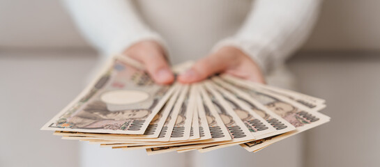 Woman hand holding Japanese Yen banknote stack. Thousand Yen money. Japan cash, Tax, Recession Economy, Inflation, Investment, finance and shopping payment concepts