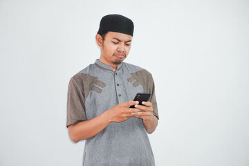 Sad face young Asian Muslim man holding mobile phone while received bad news wearing muslim clothes isolated on white background