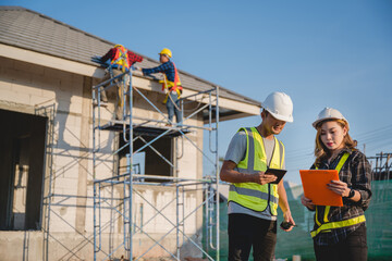 Asian male construction engineer talking to two Asian female architects a man using a tablet standing at a construction site to explain home design work