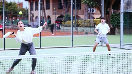 Wall Mural - Sportive men of different ages padel players hitting ball with racket on hard court in summer