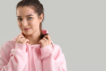 Sticker - Young woman in pink hoodie on light background, closeup