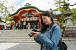 © PR Image Factory - attractive asian chinese girl photographer checking photos in slr camera with the worship hall of Fushimi Inari Taisha shrine at background in Kyoto japan