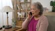 © PRPicturesProduction - asian old lady showing shocked look on face on hearing the surprising news while getting a fraud call on the cell phone in the living room at home