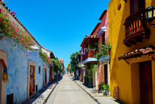 Empty street amidst colorful houses under blue sky