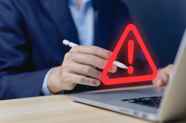 Wall Mural - businessman using laptop showing warning triangle and exclamation sign icon warning of dangerous pro
