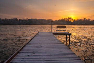 Wall Mural - frosted pier over a frozen river during a beautiful sunrise