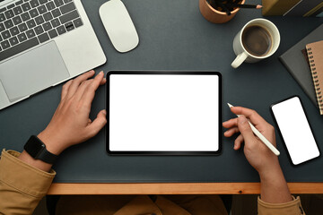 Poster - Above view of male freelancer holding stylus pen, working online with digital tablet on dark blue leather