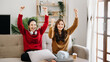 © Nuttapong punna - Two asian beauty smiling young women sitting on sofa Attractive casual girl feel happy and relax,having fun watch comedy video on TV in house. Activity lifestyles concept.