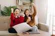 © Nuttapong punna - Two asian beauty smiling young women sitting on sofa Attractive casual girl feel happy and relax,having fun watch comedy video on TV in house. Activity lifestyles concept.
