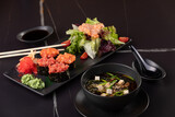 Fototapeta  - Japanese cuisine. Salmon sushi nigiri and miso soup on black plate a dark table.