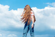 © Cavan Images - Teen ginger girl with long hair standing on the blue cloudy sky