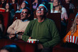 © bernardbodo - Cheerful senior watching movie in theater.