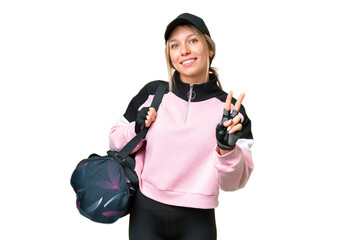 Wall Mural - Pretty sport woman with sport bag over isolated chroma key background smiling and showing victory sign