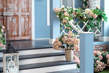 Spring Design Home With Plants And Bloom Flowers Hydrangea In Pot On Steps. House Entrance Staircase At Home Decorated For Easter. Wooden Porch Of House With Different Flowers. Terrace Of Summer House