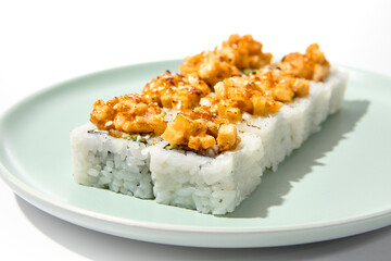 Canvas Print - Sushi topped burnt shrimp tartare. Maki sushi with shrimp and spicy sauce on ceramic plate Baked maki roll topped shrimp tartare isolated on white background with hard shadow