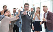 © ASDF - happy businessman standing in front of the business team and poi