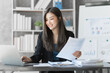 © M+Isolation+Photo - Beautiful Asian female bookkeeper doing online accounting with laptop in private accounting office, balance sheet and stock market statistics.