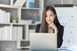 © M+Isolation+Photo - Beautiful Asian female bookkeeper doing online accounting with laptop in private accounting office, balance sheet and stock market statistics.
