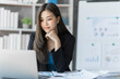 © M+Isolation+Photo - Beautiful Asian female bookkeeper doing online accounting with laptop in private accounting office, balance sheet and stock market statistics.
