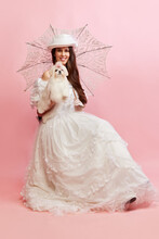 Lovely Walk. Portrait Of Beautiful Lady, Woman In White Vintage Dress Posing With Cute Dog Over Pink Background. Concept Of 19th Century, Fashion, Comparison Of Eras, History, Retro Style