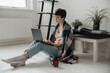 © Drobot Dean - Concentrated woman working on laptop and drinking coffee while sitting on floor