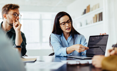 Poster - Business woman discussing a project report with her team in an office