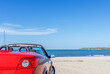 Red car on a sandy beach on a summer day.
