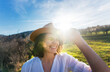 © olezzo - Young happy pretty smiling caucasian woman in a hat enjoys the sun while standing in a green spring field