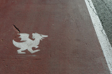 Funny pedestrian sidewalk in the medieval village of Gradara (Italy), with a middle age dragon shape over the white and red stripes on asphalt road