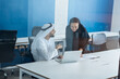 Man and woman with traditional clothes working in a business office of Dubai. Portraits of  successful entrepreneurs businessman and businesswoman in formal emirates outfits.