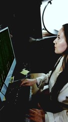 Woman programs in front of computer matrix code in animation performs professional work while her face lights up with code on her face