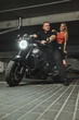 © perfectlab - Young couple hugging sitting on a motorcycle in underground parking garage