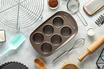 Wall Mural - Set of kitchen utensils with muffin tray, cocoa powder and sugar on light background