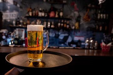 Wall Mural - waiter hand and tray with Beer into glass on bar