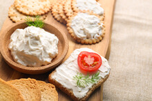 Wooden Board With Bowl Of Tasty Cream Cheese And Crackers On Table, Closeup