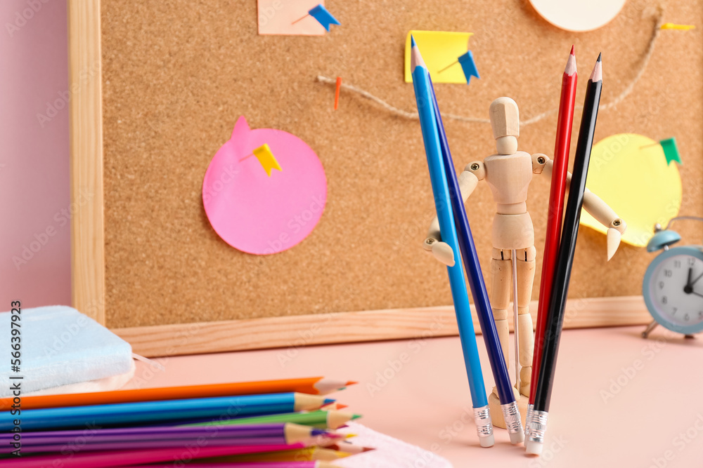 Wooden mannequin with colorful pencils on table, closeup