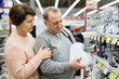 © JackF - Middle aged wife and husband picking new meat grinder in shop of household appliances.