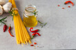 Spaghetti ingredients with garlic, oil and chili on gray background, classic italian dish, healthy mediterranean food concept, ingredients for cooking, flat lay, close up, free copy/text space.