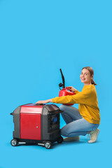 Young woman with canister and portable gasoline generator on blue background