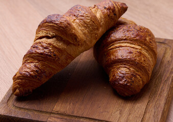 Canvas Print - Baked crispy croissant on a wooden board, breakfast