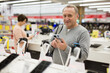 © JackF - Mature caucasian man looking at camera and smiling while choosing smartphone in electronic shop.