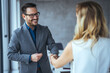 Business people shaking hands after successful meeting. Businessman And Businesswoman Shaking Hands In Office. Businessman shaking hands with his female partner celebrating successful teamwork.