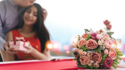 Flower bouquet decor on table blur background with young adult couple valentine dating