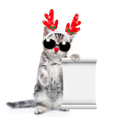 Poster - Funny kitten dressed like santa claus reindeer Rudolf holds glass of champagne and shows empty list. isolated on white background